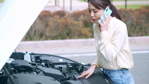 Young asian woman opening bonnet of vehicle. Road service. Roadside assistance.