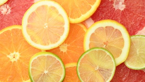 Citrus fruits slices such as oranges, grapefruits, lemons and limes, rotating, top view