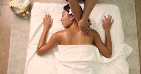 Young Asian woman receiving an oil massage on her back at spa salon by professional masseuse, Spa treatment and aroma oil massage concept