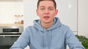 Pleasant, smiling male blogger records training video or gives client one-on-one language lesson. Portrait young male student looking into camera, holding video call with friends.