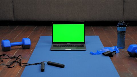 Modern laptop computer display mock up chroma key green screen stands on fitness or yoga mat on home sofa background. Online remote distance sports video call webcam virtual webinar master class chat