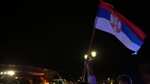 Perast, Montenegro - 15 july 2020: Man waves large Serbian flag at night, close-up