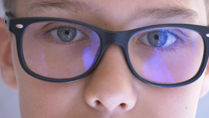 Teenage boy with blue light blocking glasses opening eyes and looking direct at camera. 4k video