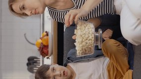 Mom and her little son are watching a thriller while eating popcorn at their home. Concept of having fun, spending time with children at home.Video for the vertical story.