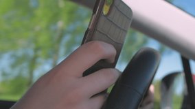 A young man driving and texting on the smartphone could lead into a car accident . selective focus