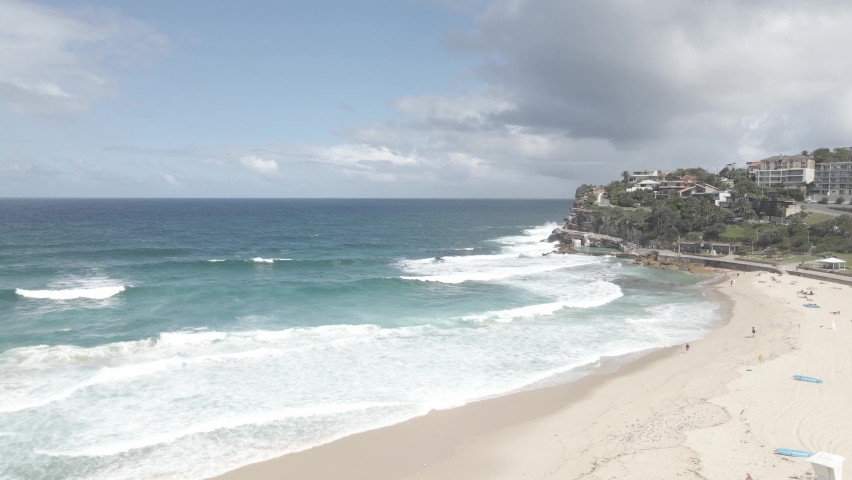 Aerial View Of Bronte Beach Coastline with Foamy Ocean Waves And Tourists In Eastern Suburbs, Sydney, New South Wales, Australia - drone shot