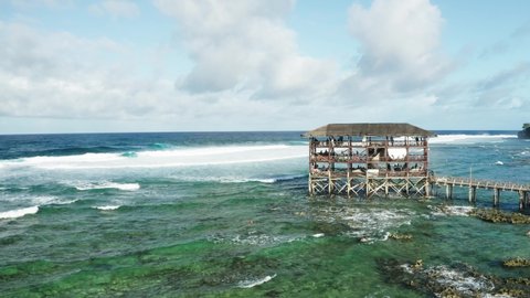 Cloud 9, well-known surfing spot on Siargao Island, Philippines. Observation tower for jury and tourists during surfing competition. Turquoise shallow water. Aerial view, medium angle, 4k