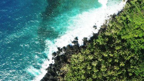 Aerial top down view of coast line of Siargao Island, Philippines. White waves crushing over rocks, turquoise water and palm trees. Peaceful and relaxing diagonally view