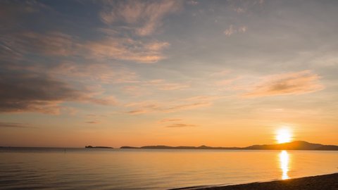Golden sunrise at horizon, 4k timelapse of yellow sky bright sun and orange clouds in morning at the sea. reflection of sun shine on the water surface. panoramic view, beginning of the day at the sea.