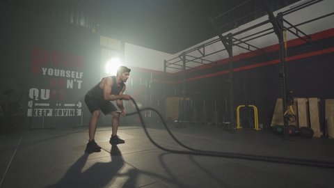 Middle east man doing battle ropes for cardio. Muscle strength training workout at gym fitness center club. Exercise indoor with sport equipment. Athletic. People lifestyle.