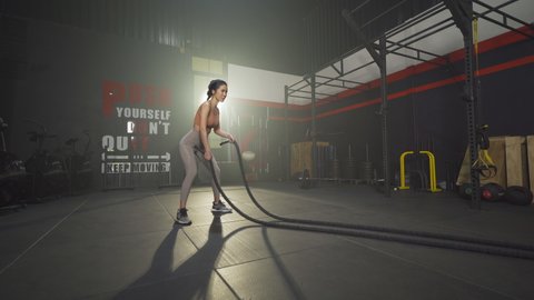 Asian woman doing battle ropes for cardio. Muscle strength training workout at gym fitness center club. Exercise indoor with sport equipment. Athletic. People lifestyle. Recreation