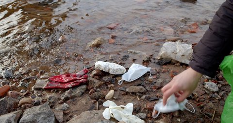Hand collects plastic waste on the shore. These are Refined Petroleum Products (polystyrene, polyethylene, PET, polypropylene, styrofoam). Plastic pollution and environmental problem concept.