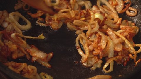 Close-up of delicious onion rings frying and caramelizing in sugar on the pan