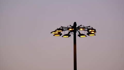 Time lapse of turn on modern street lamps at sunset.