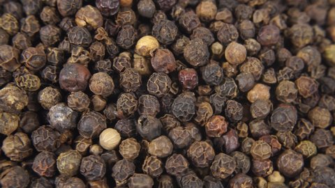 Pile of black peppercorns, a dried fermented seeds, top view. Peppercorn background. Mixed multi coloured peppercorns close-up. Food dark background. Dry aromatic black pepper seeds. Macro view.