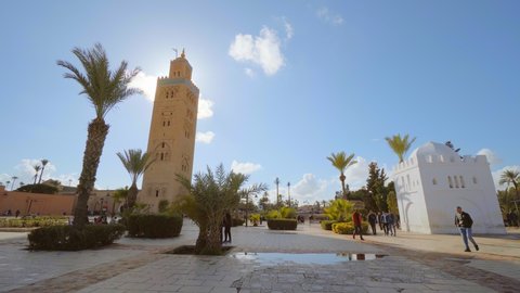 Marrakech, Morocco - November 2019: Local people walk past the Koutoubia Mosque. Beautiful sunny day, summer, Africa, traveling, square, architecture, islamic. 4K Video Footage