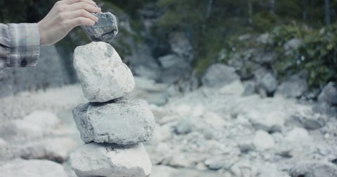 Female hand puts stone on stack or cairn relaxation in Alps close up
