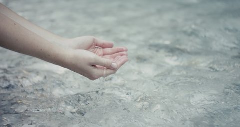 Female hands capturing crystal clear Alps wild river water close up