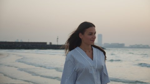 Close up view of attractive young brunette woman walking on the beach in Dubai