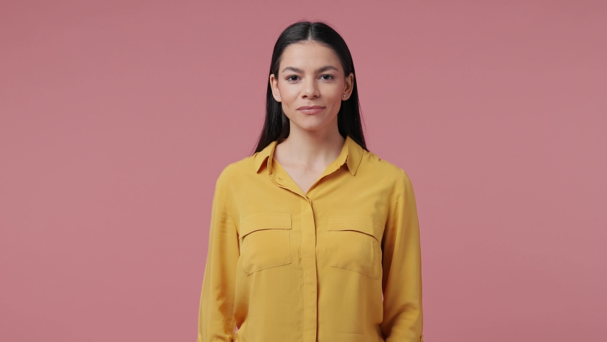 Smiling beautiful brunette young latin woman 20s years old in casual yellow shirt posing isolated on pastel pink color background in studio. People sincere emotions lifestyle concept. Looking camera Royalty-Free Stock Footage #1070762320