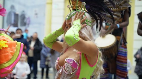 MOSCOW, RUSSIA - FEBRUARY 29, 2020: Celebration of Brazilian carnival. Beautiful girl in colorful festive costume decorated with rhinestones and feathers are dancing samba at street