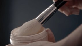 Close-up of female hands mixing face powder. Slow motion of makeup brush collecting cosmetic substance. High quality FullHD footage