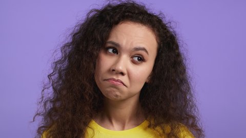 Portrait of hesitant girl on purple background. Young lady doubts, weighs the pros and cons, but then agrees, nods head in affirmative. Why not concept.