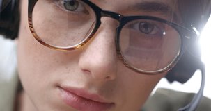 Close up Face of Girl in Eyeglasses and Headset looking Focused into Camera. Having Blue Eyes with Long Eyelashes and Beautiful Face with Freckles. Attractive Call Center Agent. Distance Work.