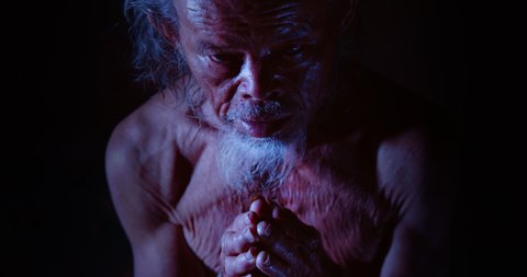 Slow motion night scene, face of Asian old man, white hair, white beard, white beard, rough skin, scary face, mysterious looking, chanting magic, used in the concept of occultism, sorcerers, mysticism