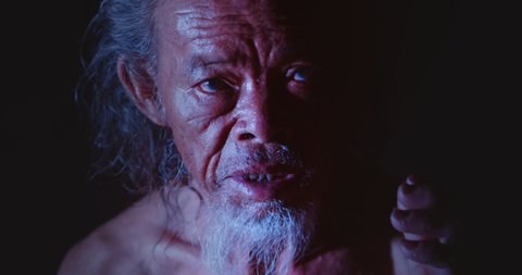 Slow motion night scene, face of Asian old man, white hair, white beard, white beard, rough skin, mysterious look. Used in the concept of occultism, sorcerers, mysticism, sorcery