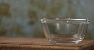 Raw pasta in the glass bowl on wooden table background, slow motion, 4K.