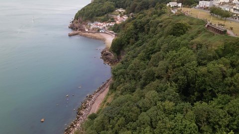 Aerial flyover beautiful landscape with green cliff hills and rocky beach and blue shore in Torquay City,Devon.