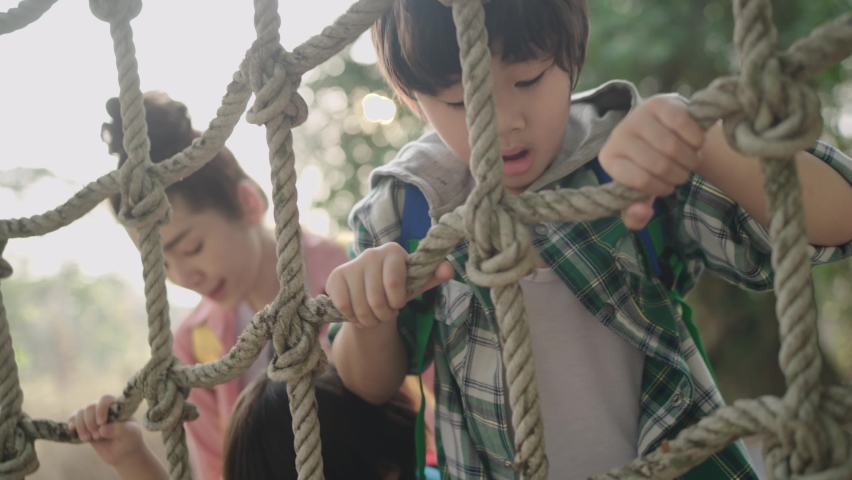 Focus Rope mesh, Slow-motion.Asian boys learn to climb a rope wall To enhance the development of the body Was in the park on holidays with close supervision by parents. Royalty-Free Stock Footage #1070795008