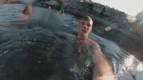 Handheld shot of young man holding action camera and swimming in lake with friends. They are waving and posing - Powered by Shutterstock - Get 15% off with code: PIKWIZARD15