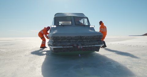 Rescue team getting in hovercraft and sailing across frozen lake in winter. Professional coast guards riding air-boat having emergency crossing arctic water area