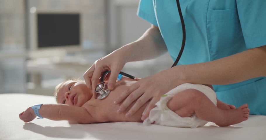 Pediatric doctor checking up newborn baby with stethoscope in hospital. Cropped shot of neonatologist with stethoscope examining infant in pediatrics clinic Royalty-Free Stock Footage #1070798329