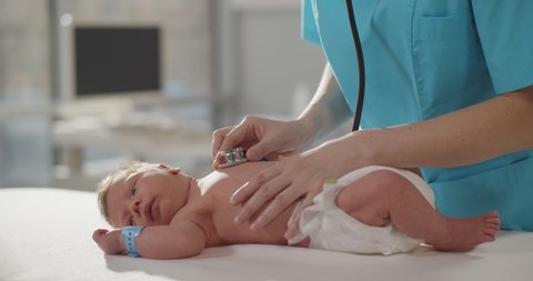 Pediatric doctor checking up newborn baby with stethoscope in hospital. Cropped shot of neonatologist with stethoscope examining infant in pediatrics clinic