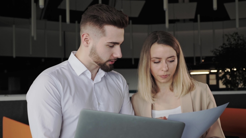 Male and female colleagues discuss financial data analyzing marketing result in report using documents having business conversation help coworker with corporate project stand in loft office. Royalty-Free Stock Footage #1070800387