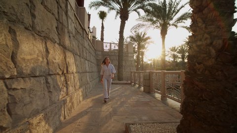 Woman walking on the riverfront in luxury residential neighborhood in Dubai. Front view of a woman walking along the river in United Arab Emirates