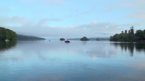 Morning mood - lake with reflections looping with ducks. Forest and reflections, islands. Mystical scenery or blue background. Lake Windermere - England tourist attraction. Poetic Wordsworth country.