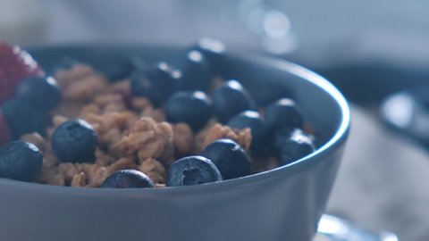 Sliding shot of berries blueberry and healthy granola muesli. Healthy breakfast oat granola with blueberries, strawberries and milk. Close up shot.