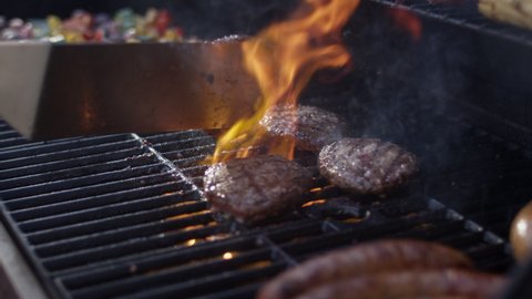 Huge flames engulf juicy grilled burgers at a summer cookout