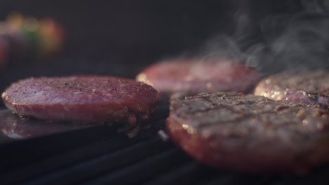 Close up shot of a juicy burger getting flipped on the grill