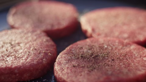 Close up slow motion shot of burgers before they hit the grill