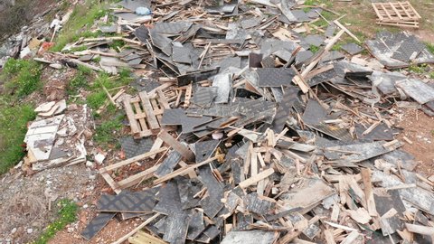 Open illegal dump: destroyed, broken and strewn wood, tiles and debris on a field. Fly dumping (tipping) is depositing rubbish and untreated hazardous materials onto land causing environment pollution