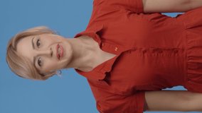 The woman says she doesn't like it by cutting his throat with his hand.The young woman in front of a blue background disapproves of something he dislikes with his head and hands.Video for the vertical 