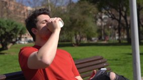 A slow-motion of a bearded Spanish man drinking coffee while texting in the park in HD