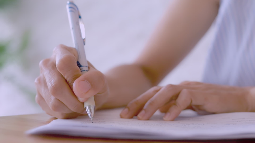 HD Close up hand of business women use pen writing document paper. Female hand close up writing with a blue pen on a white sheet. Woman writes information on a piece of paper.