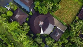 4K Video from a drone flying over a palm rainforest with a round building in the center and sits in the center of religious people