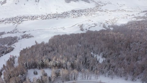 Drone clip of Livigno, magical winter destination for your holidays in Italy, clouds and a light snowfall, with sun flares